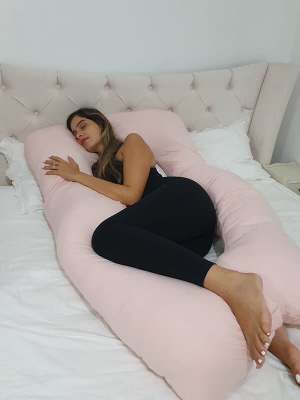 אישה ישנה על כרית הריון ורודה